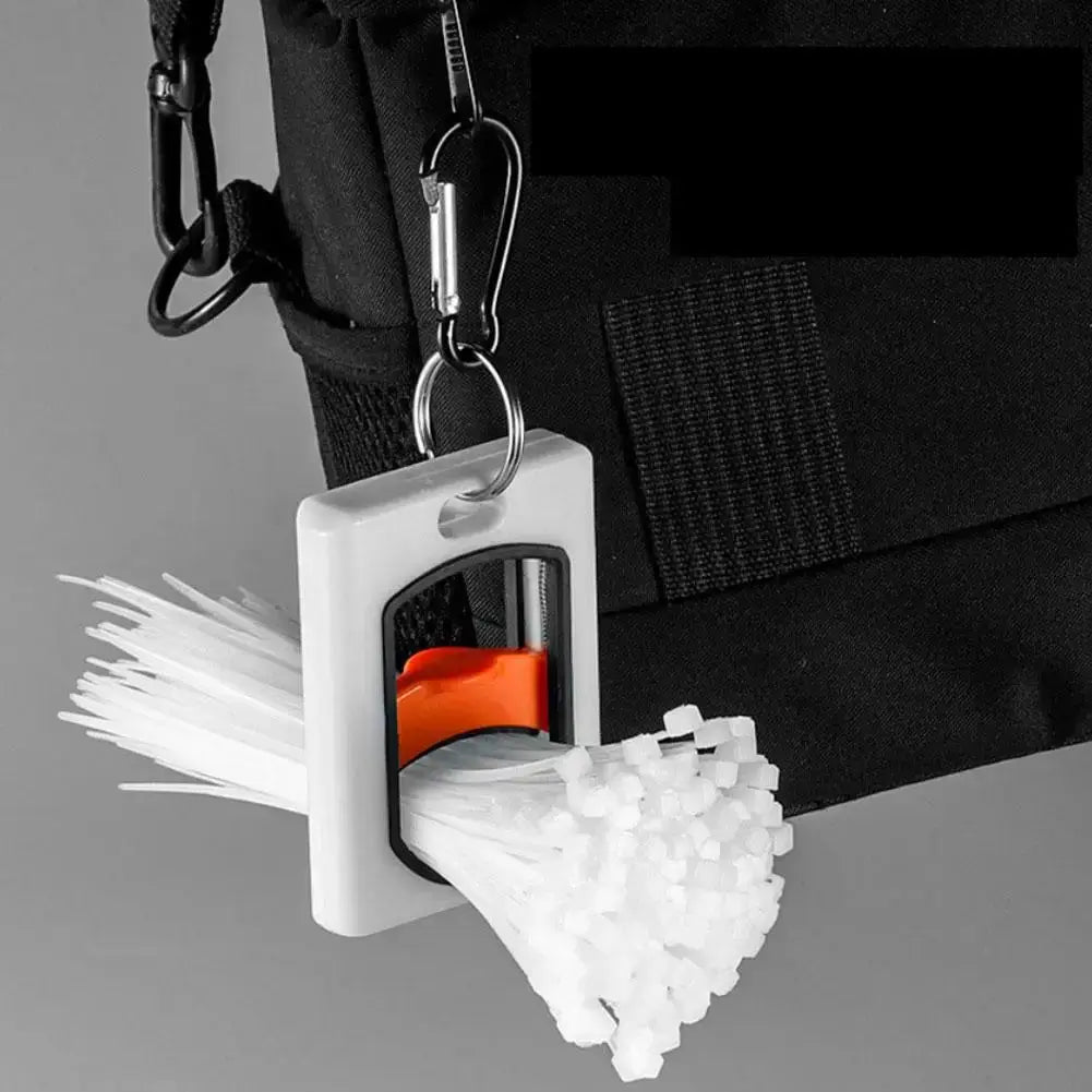 Square white cable tie organizer with orange slider; stores white zip ties and attaches to a backpack via metal ring.