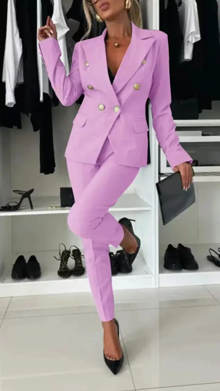Pink women's two-piece office suit with V-neck double-breasted blazer and tapered pants, gold buttons.