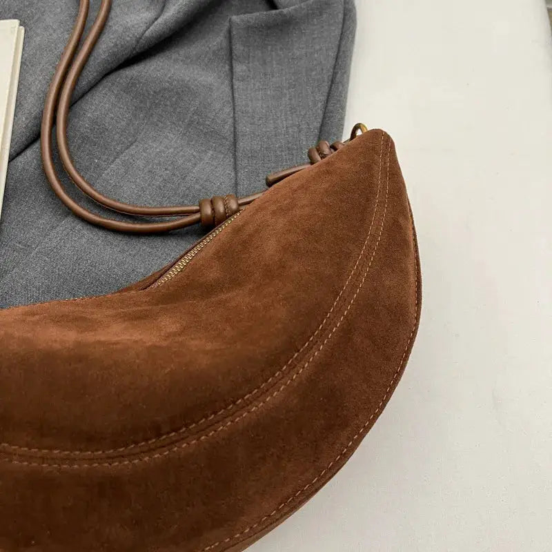 Faux suede shoulder bag with crossbody strap in brown, curved dumpling silhouette and zipper