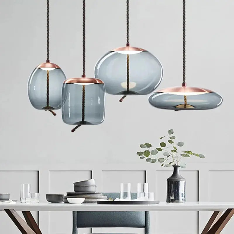 Pendant lamp set: blue glass shades with copper tops on hemp rope cords, four minimalist hanging lights.