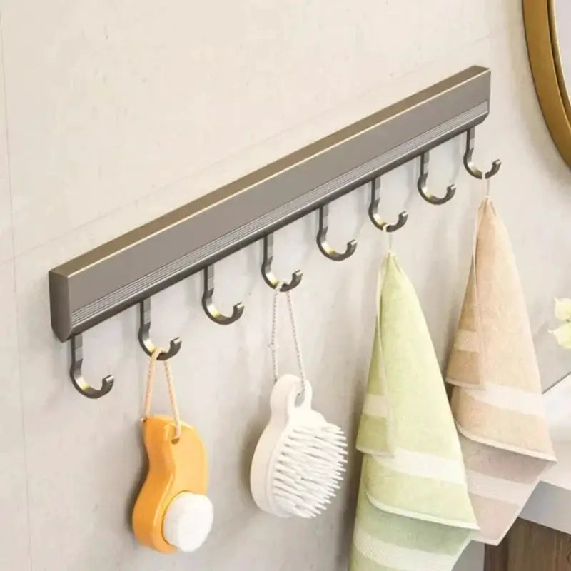 Wall-mounted kitchen storage rack in gray aluminum alloy with multiple hooks, holds a sponge and bristle brush and two towels.