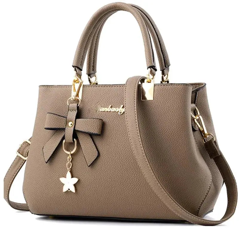 Elegant taupe pebbled leather shoulder bag with bow accent and star charm, top handles and crossbody strap