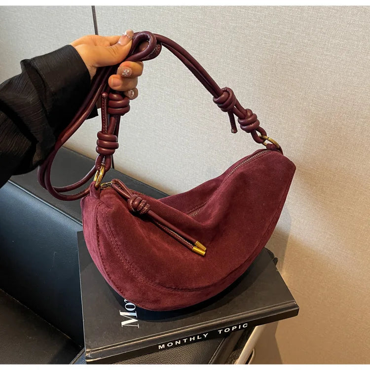 Faux suede dumpling-style shoulder bag in burgundy with knotted handles and gold-tone hardware, single crossbody bag