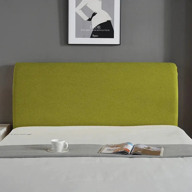 Green upholstered bed headboard with textured fabric in a modern bedroom.