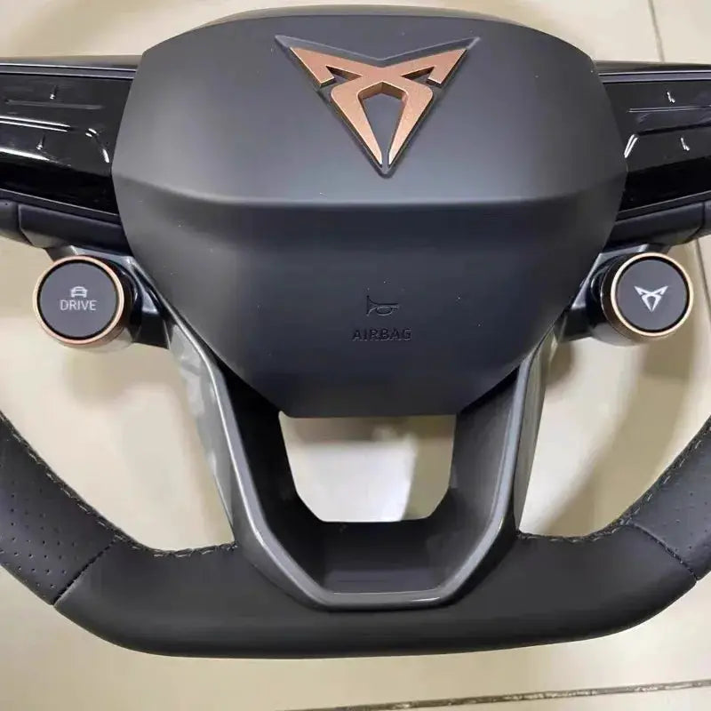 Steering wheel with copper Cupra emblem on black leather, airbag text visible