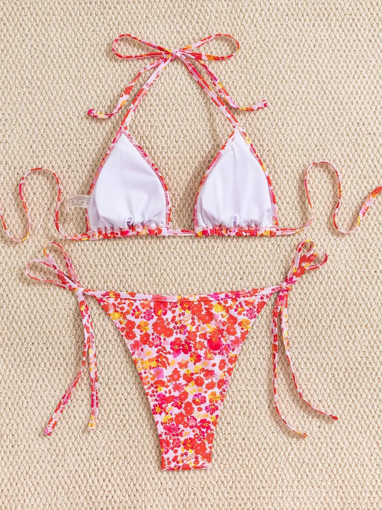 Two-piece bikini set by Simples Market with floral print; white triangle cups with pink trim and adjustable tie-side bottoms