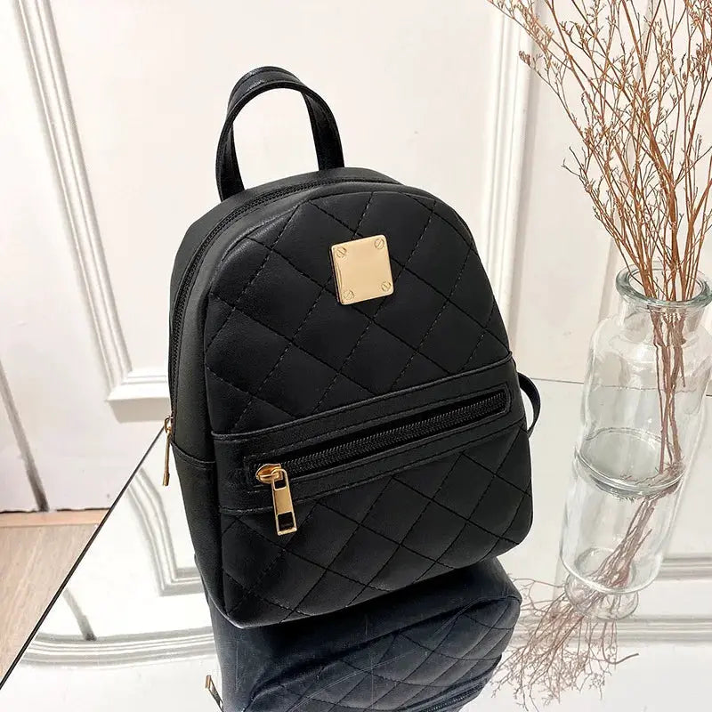 Embroidered quilted black backpack with gold hardware and front zip pocket by Simples Market