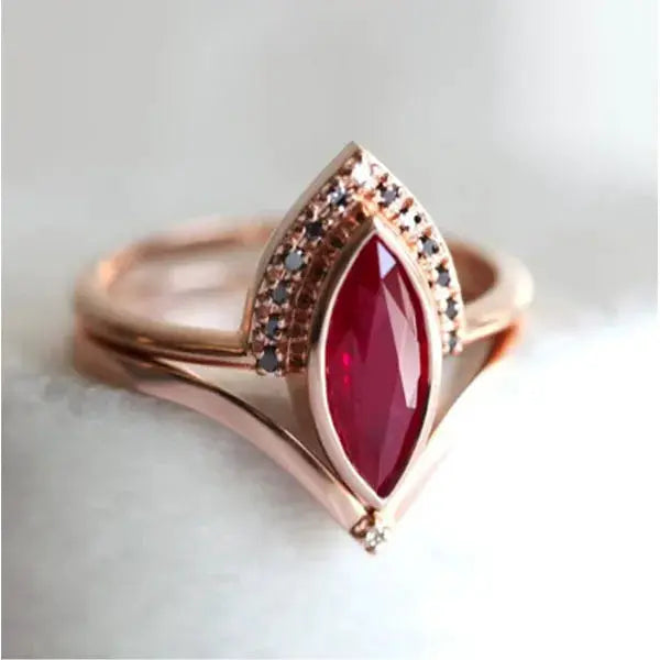 Rose gold engagement ring with a marquise red center stone and white zircon accents.