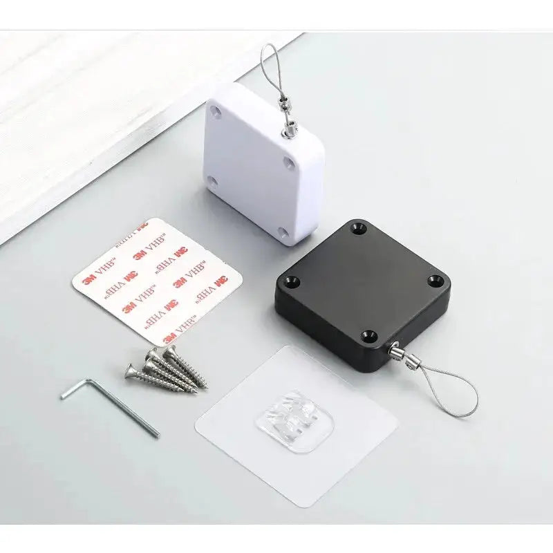 Two automatic drawstring door closers by Simples Market; white and black units with screws and adhesive pads