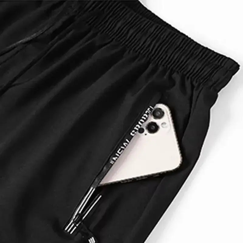 Men's plus-size gym shorts by Simples Market, black with elastic waistband and side pocket holding a phone