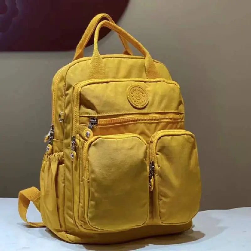 Backpack by Simples Market: yellow waterproof nylon with multiple pockets and soft handles