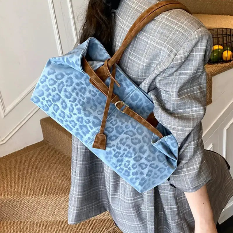 Blue leopard-print PU leather shoulder bag with brown straps carried by a person in a gray plaid blazer