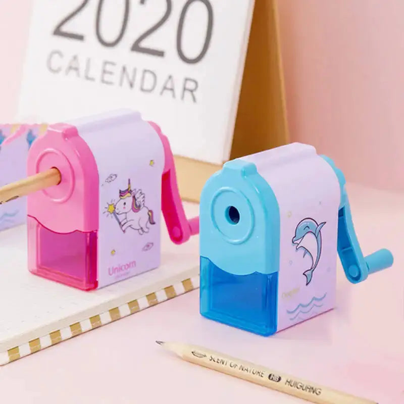 2 mechanical pencil sharpeners featuring unicorn and dolphin designs in pink and blue with transparent reservoirs.