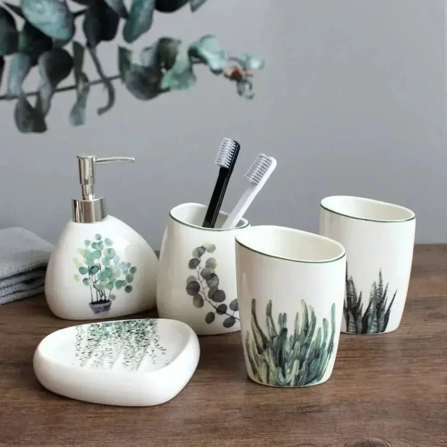 White ceramic bathroom set by Simples Market with soap dispenser, toothbrush holder, 2 cups and dish with green pattern.