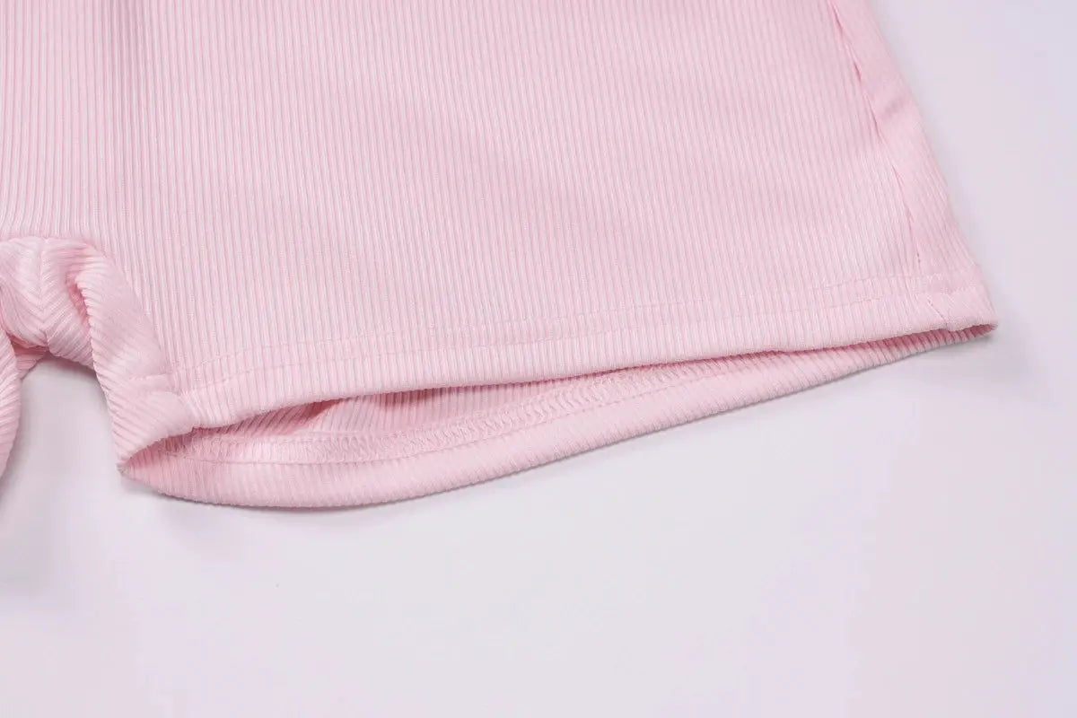 Playsuit in pink ribbed fabric close-up showing sleeve hem and knit texture