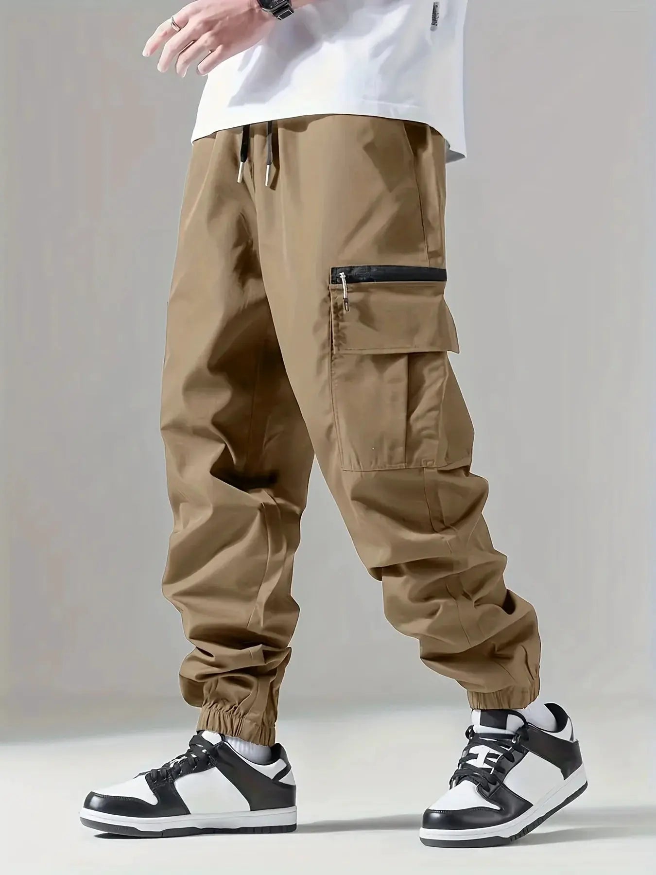 Men's tan cargo pants with thigh zip pocket, multiple pockets, drawstring waist, and elastic cuffs