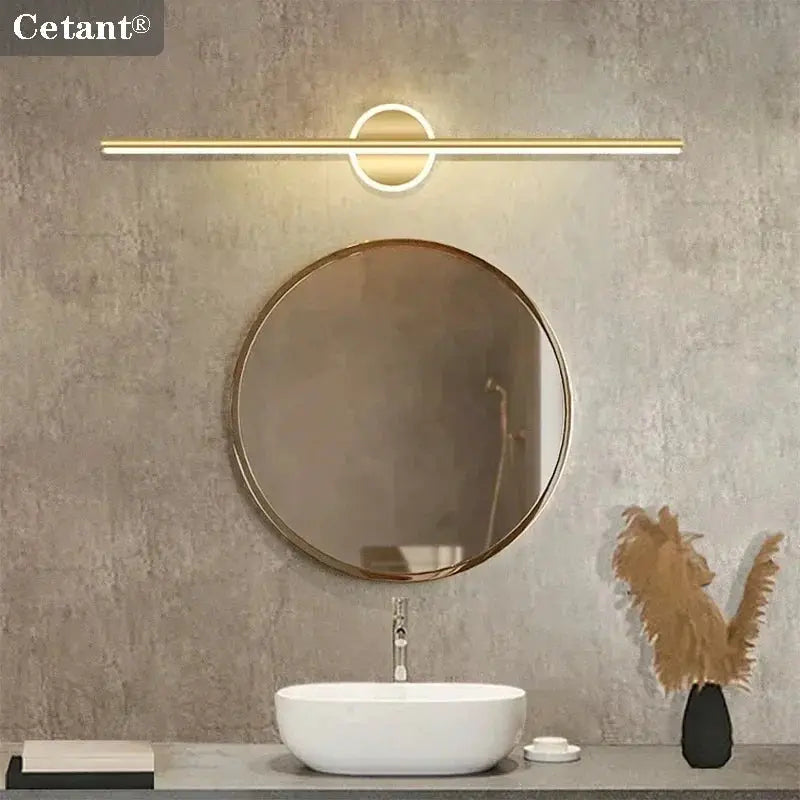 Modern LED wall lamp by Cetant, gold finish long strip with circular accent above round bathroom mirror