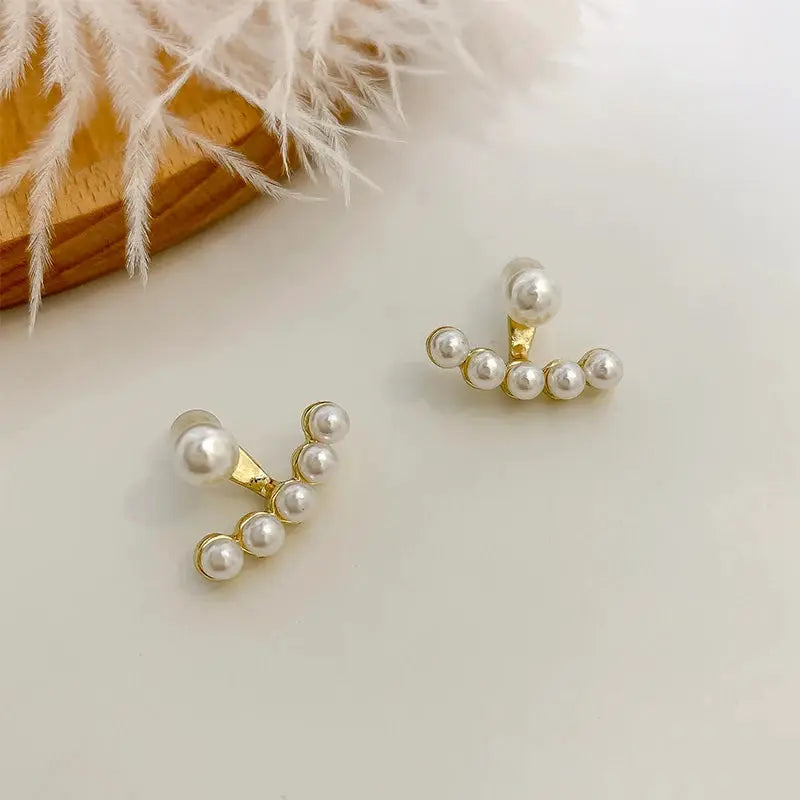 Pair of imitation pearl stud earrings from Simples Market featuring gold-tone curved bars with white pearls