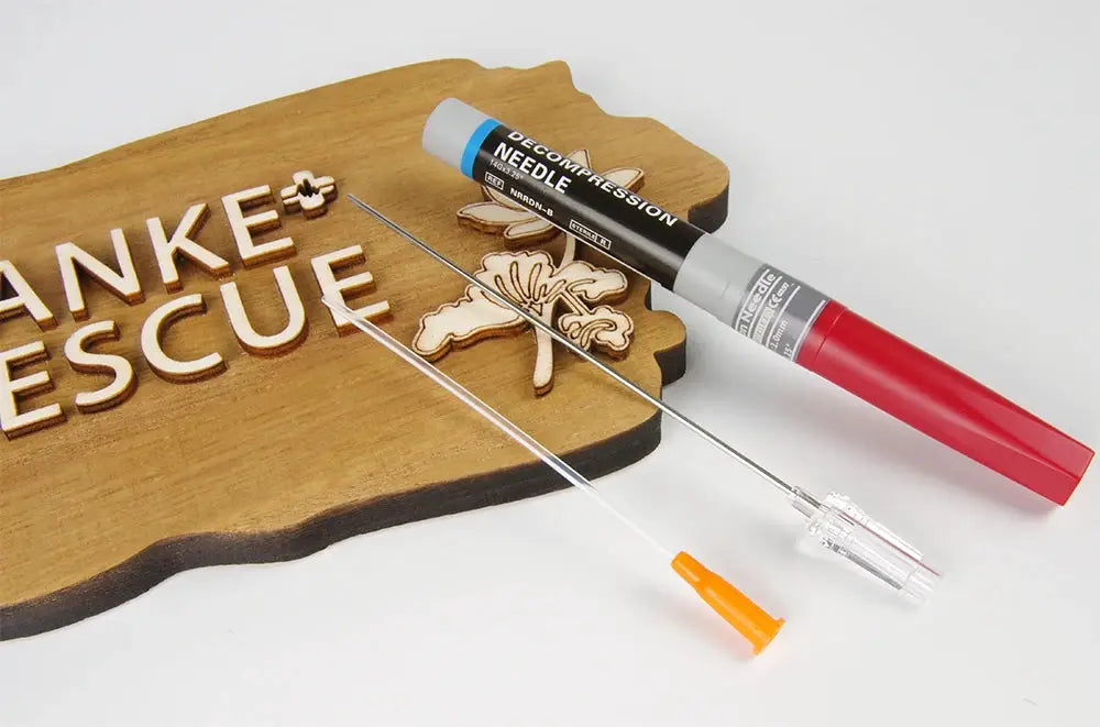 Decompression needle kit for pneumothorax with red-handled device, clear catheter and long needle, on a wooden rescue board