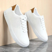 Men's white leather sneakers with perforated sides, tan heel patch, lace-up.