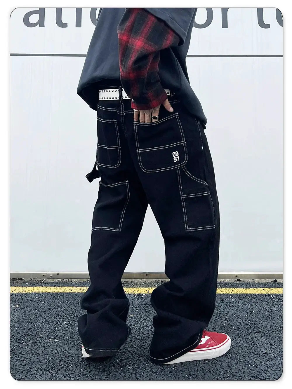 Men's black retro work jeans with cargo pockets, white contrast stitching, and a white studded belt.