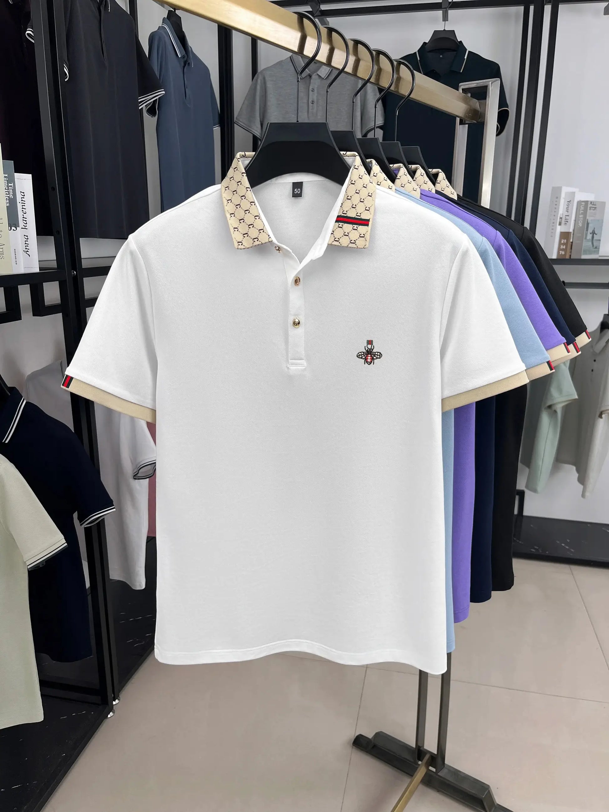 White polo shirt with beige patterned collar, Little Bee embroidery, and red-green trim.