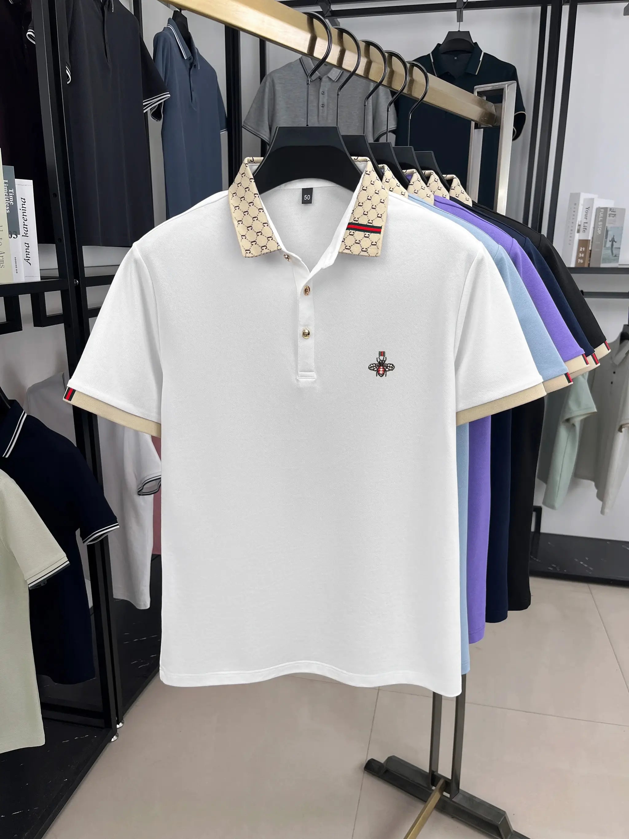 White polo shirt with beige patterned collar, Little Bee embroidery, and red-green trim.
