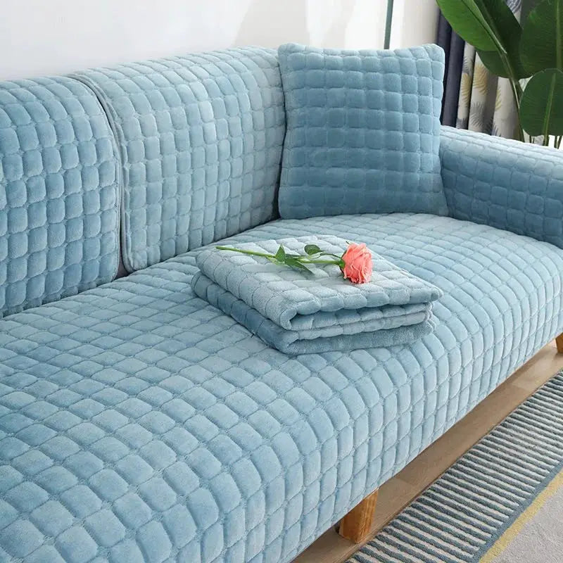 Blue velvet quilted sofa cover with matching cushion covers on a living room sofa.