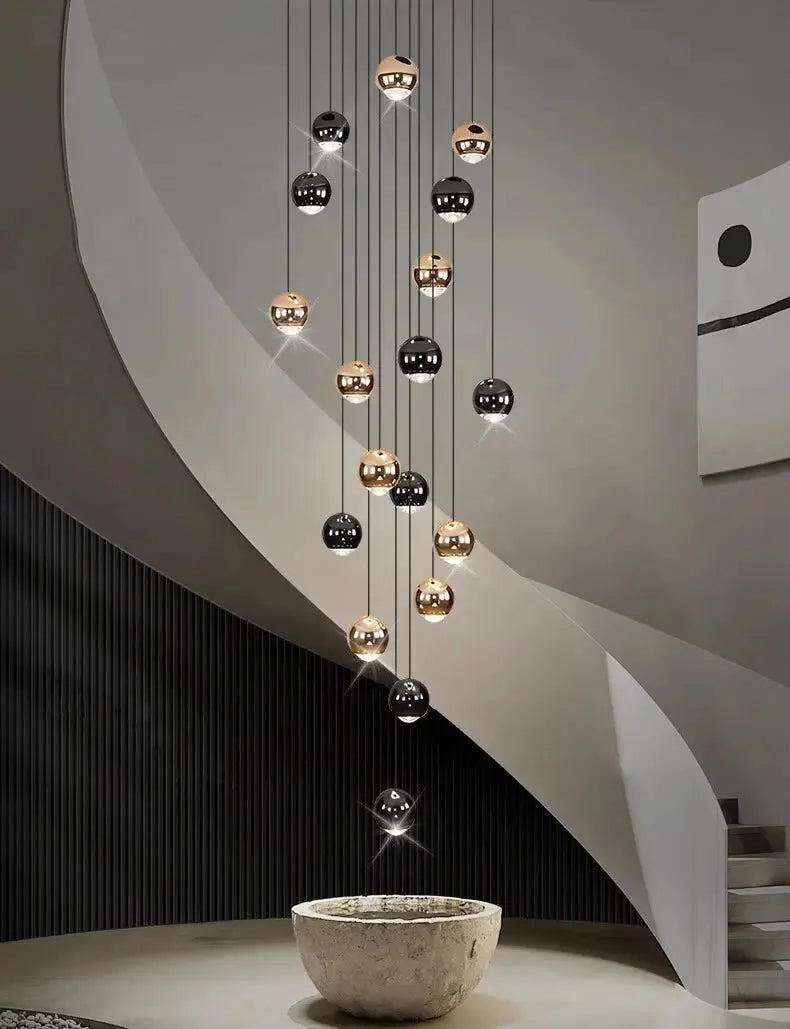 Modern pendant light chandelier with black and brass orbs, hanging over a stone bowl.
