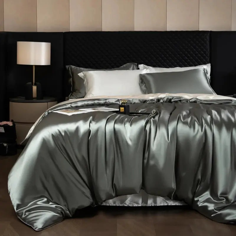Silk bedding set in silvery gray satin with duvet cover, fitted and flat sheets, and pillowcases on a king bed