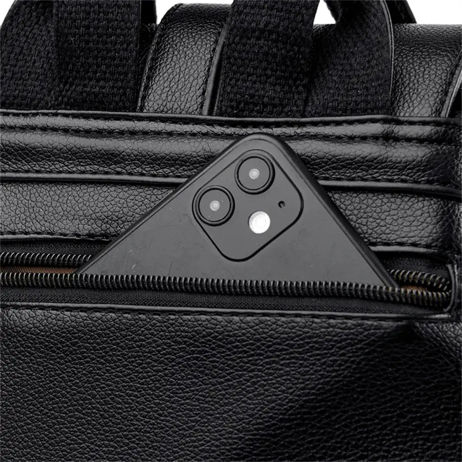Simples Market black leather backpack with front zipper pocket and a phone tucked inside