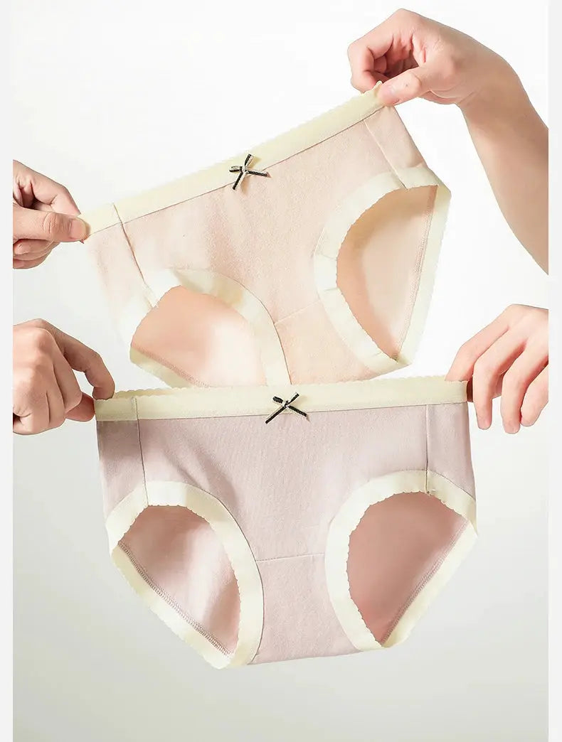 Two pastel pink and peach cotton panties with cream trim and small bow accents.