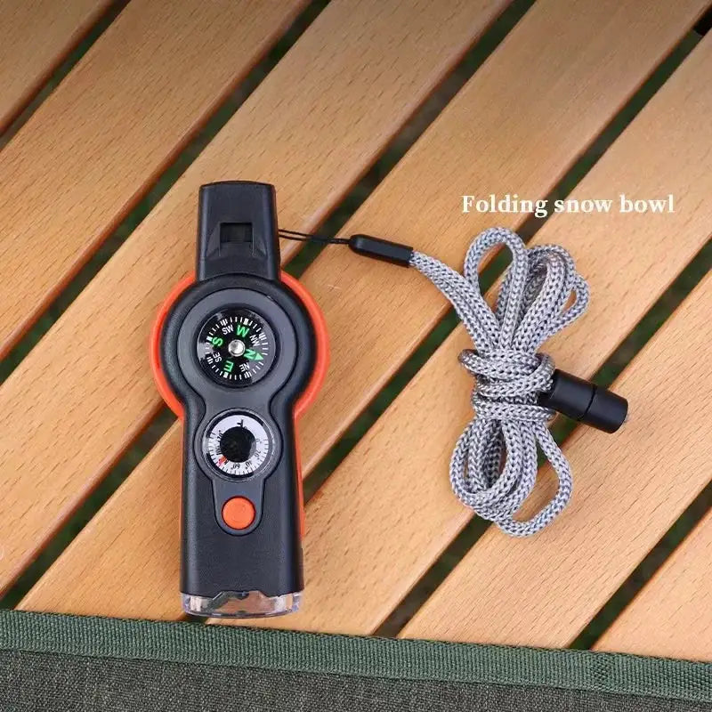 Simples Market 7-in-1 outdoor survival whistle with compass, black body, orange trim, and gray lanyard