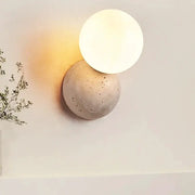 Wall lamp with cream round LED globe on textured stone cave base by Simples Market