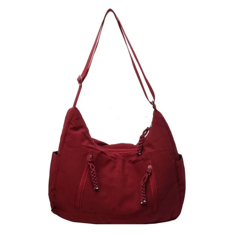 Trendy women's soft-cloth shoulder bag in red with braided zipper pulls, front pockets, and crossbody strap