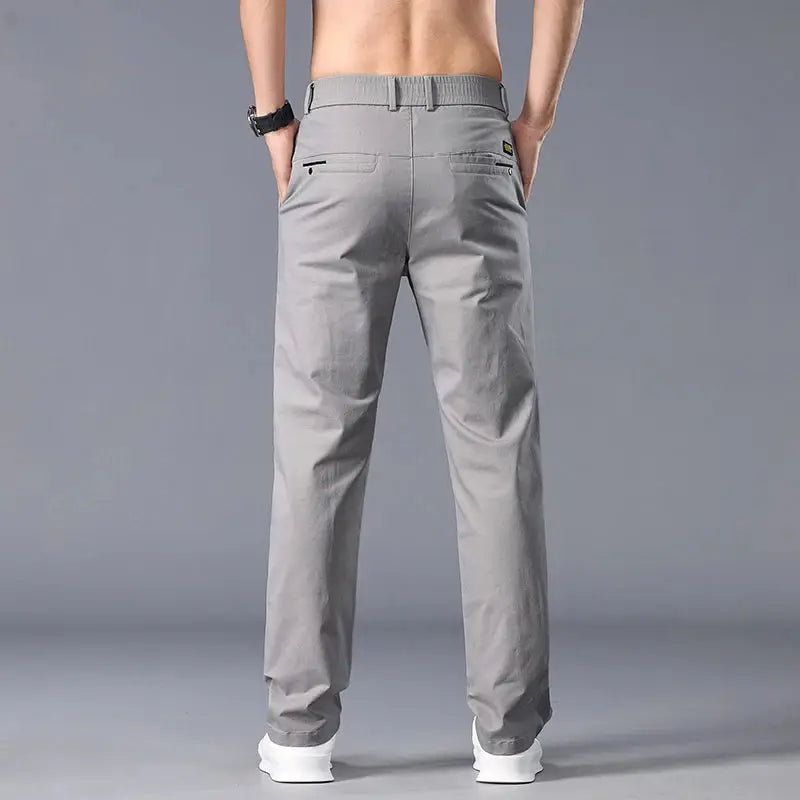 Casual men's straight-fit chinos in light gray shown from the back with belt loops and two back pockets on a model