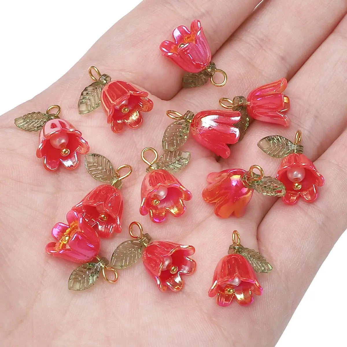 Acrylic lily-of-the-valley beads in pink translucent with gold loops and green leaves