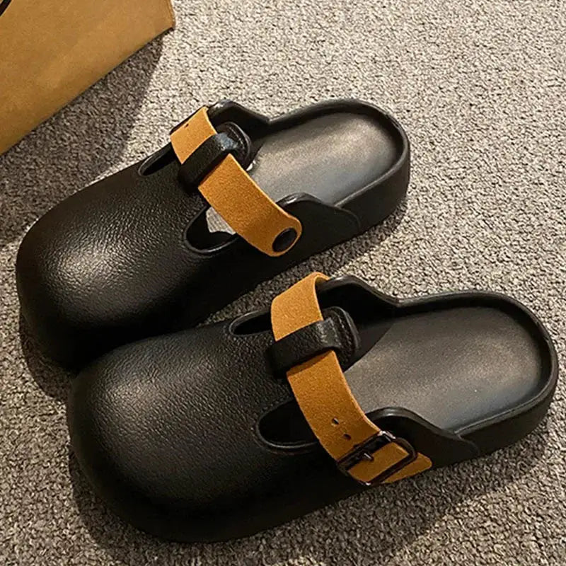 Pair of black EVA clogs with tan buckle straps for women.