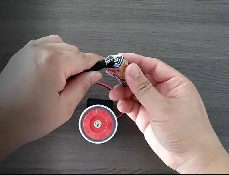 WOFEA 130dB wired mini sound alarm siren; red center, white rim, connected to a small battery