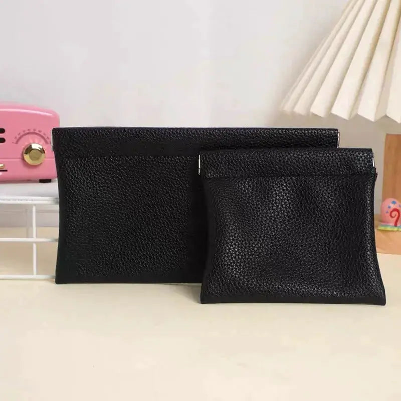 Two black self-closing artificial leather wallets: a long wallet and a compact ID holder.