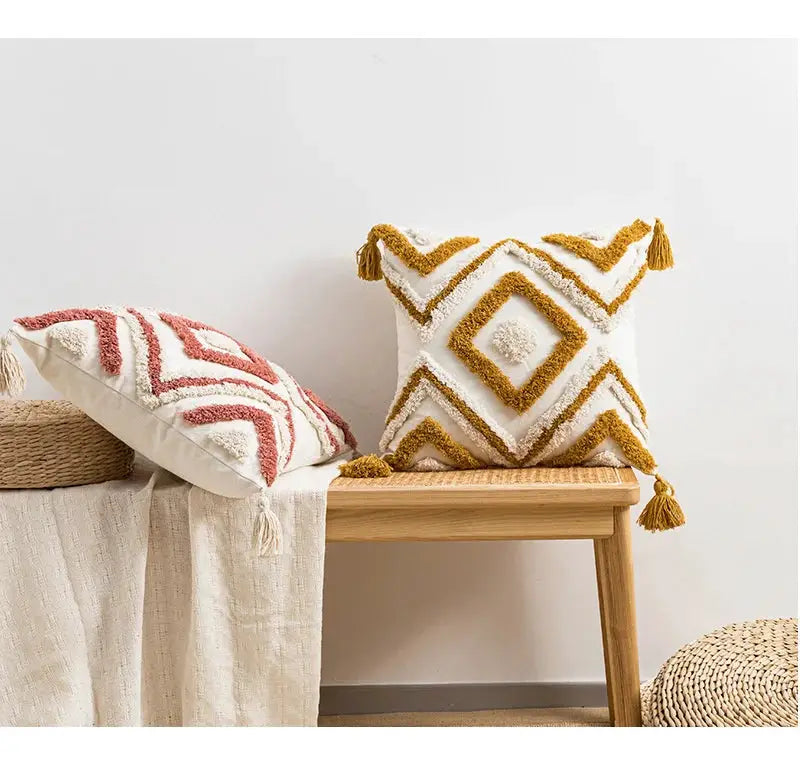 Boho decorative pillow covers; tufted white cushions with gold diamond patterns and a red geometric pillow on wooden bench