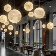 Nordic Moon LED pendant lights by Simples Market; warm moon-glow glass spheres hanging in a cafe, multiple fixtures