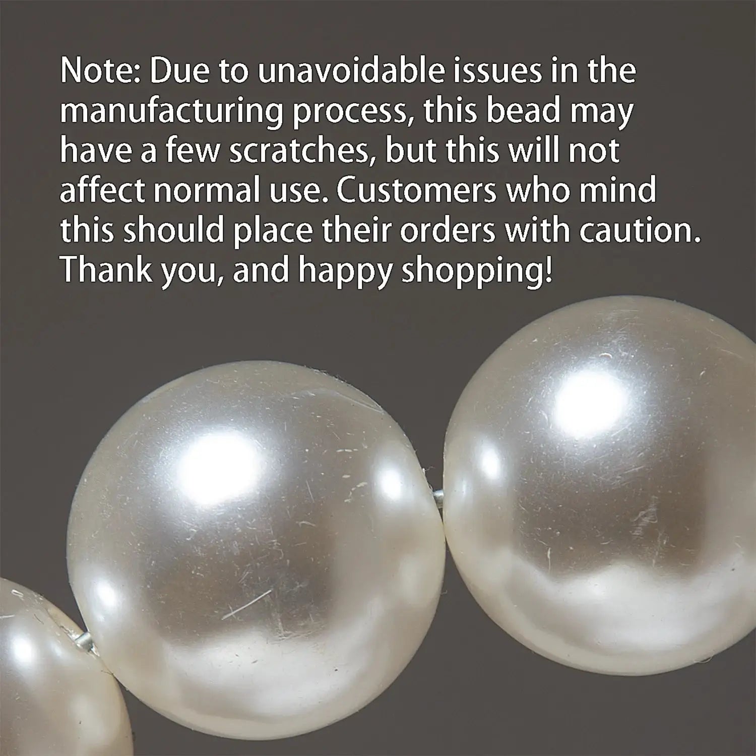 Pearl bead strand; white glossy faux pearls against a gray background