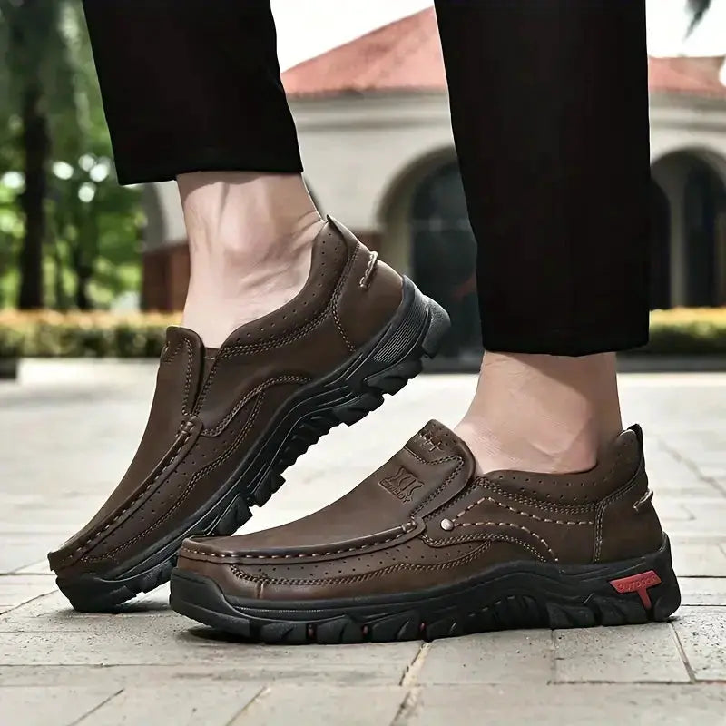 Men's handmade brown leather slip-on loafers with moccasin-style stitching and rugged non-slip outsole.