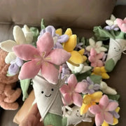 Plush flower bouquet with pastel pink, yellow, and purple petals and smiling-face fabric stems.