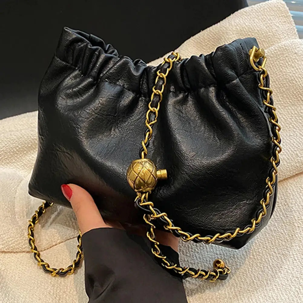 Women black faux-leather crossbody bag with gold chain strap and spherical charm