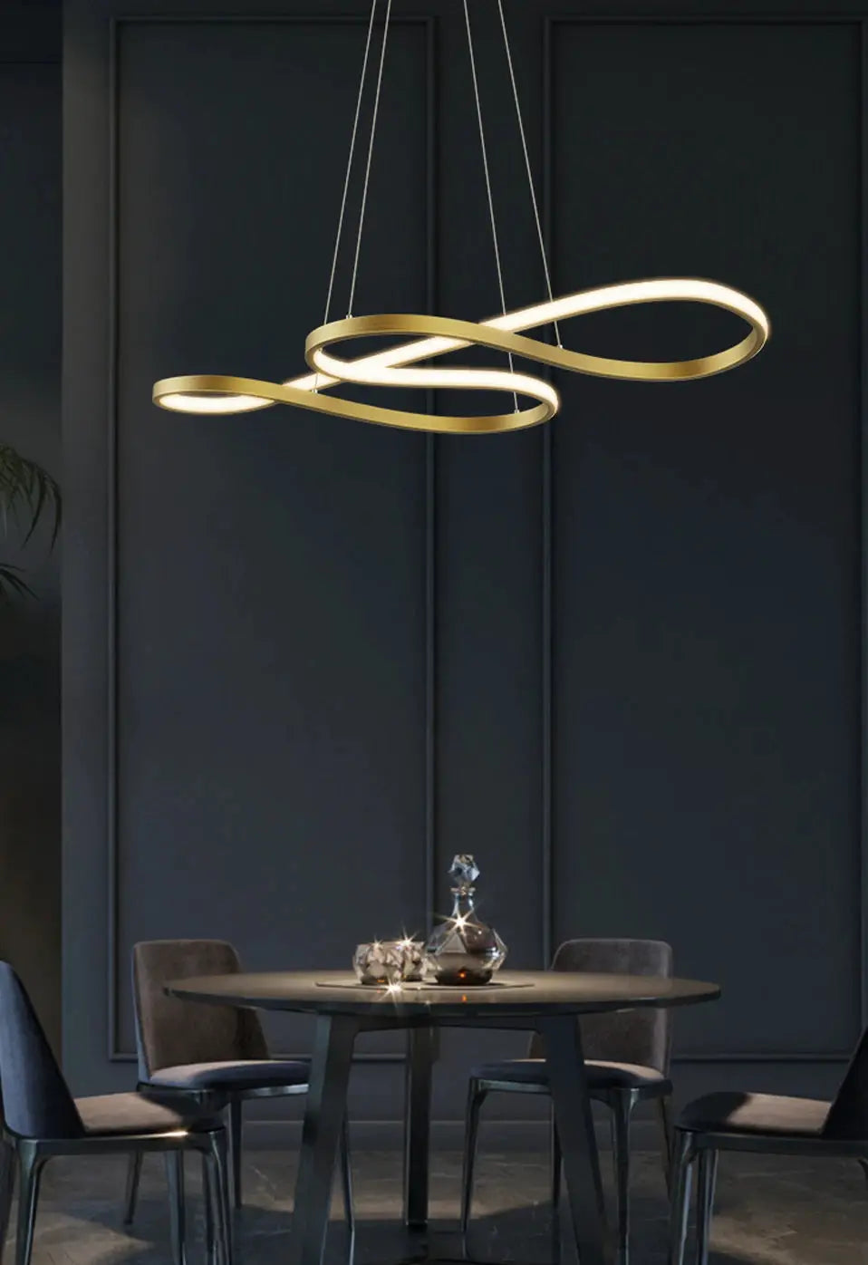 Modern gold-toned pendant light with intertwined looping design over dining table.