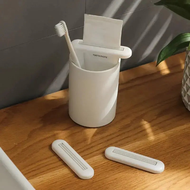 Toothpaste squeezer set in white with two extra bars and a toothbrush in a cup