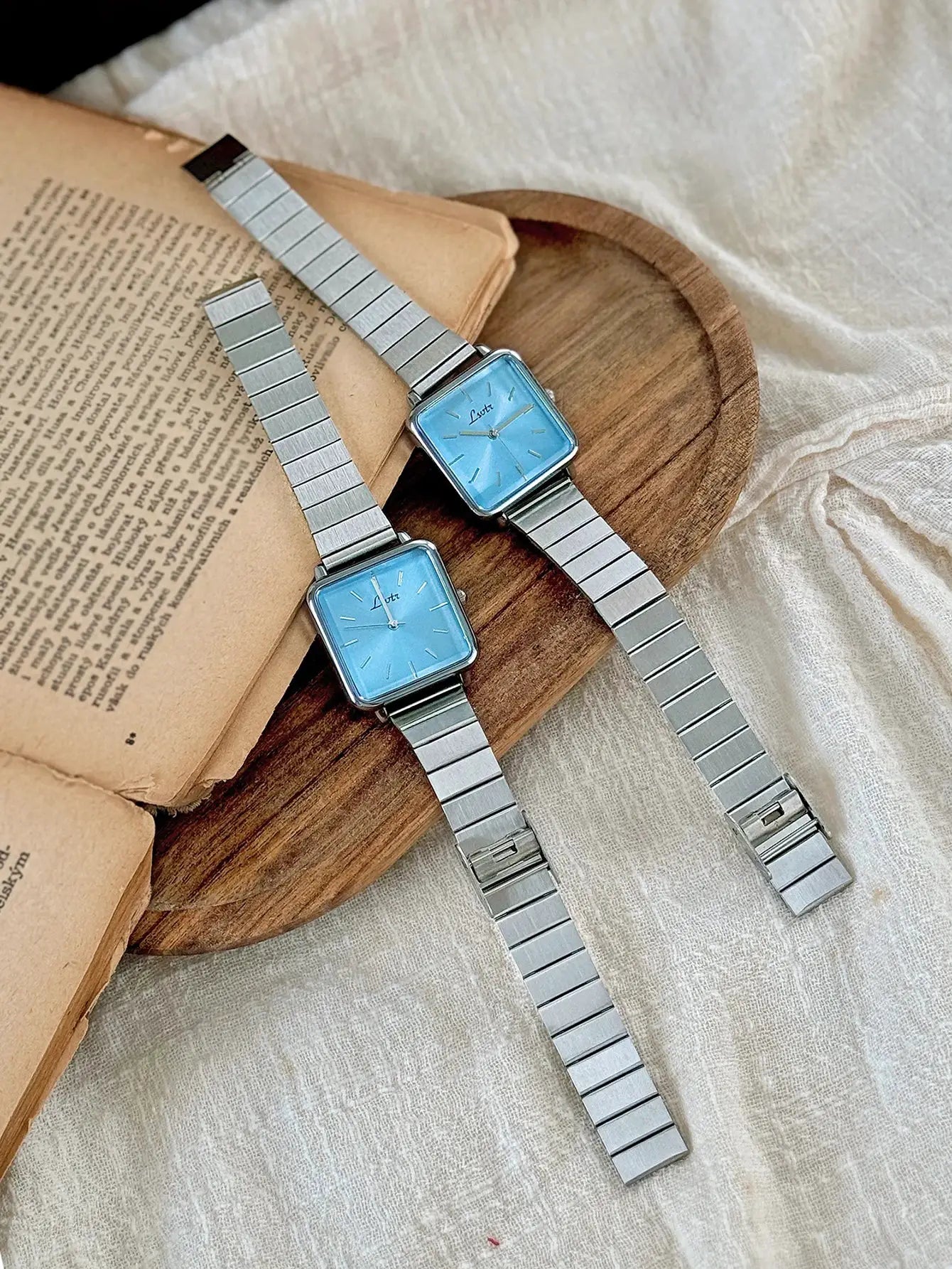 Two Simples Market women's stainless steel square-faced watches with blue dials.