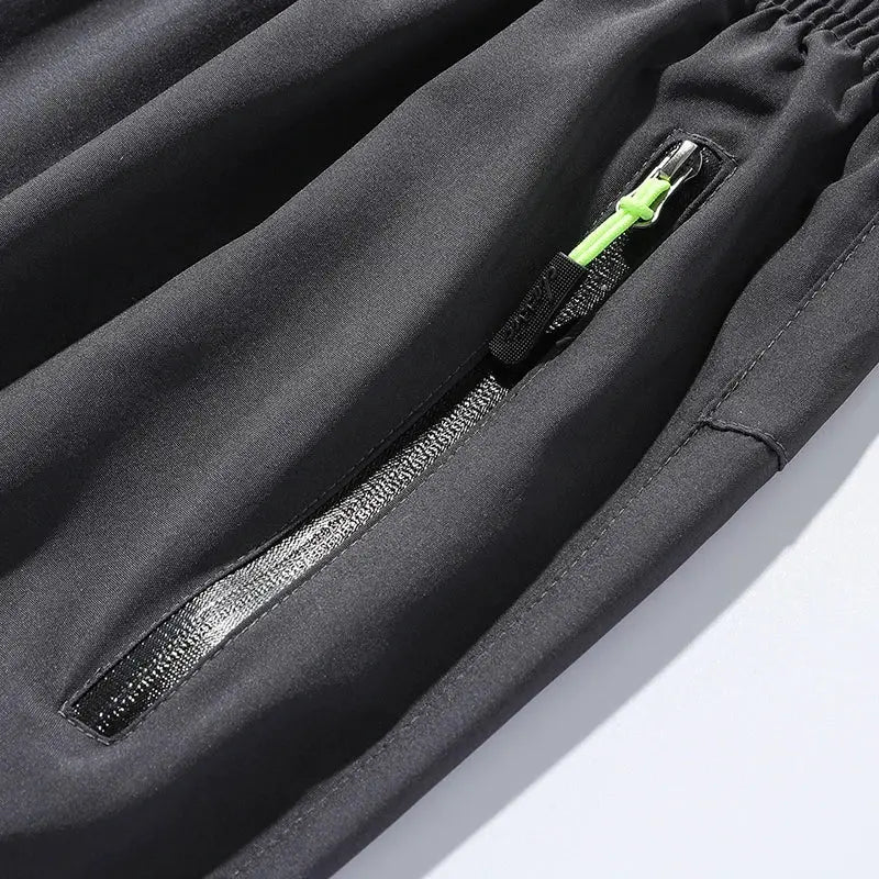 Breathable men's jogger pants by Simples Market with zip pocket and neon green zipper pull.